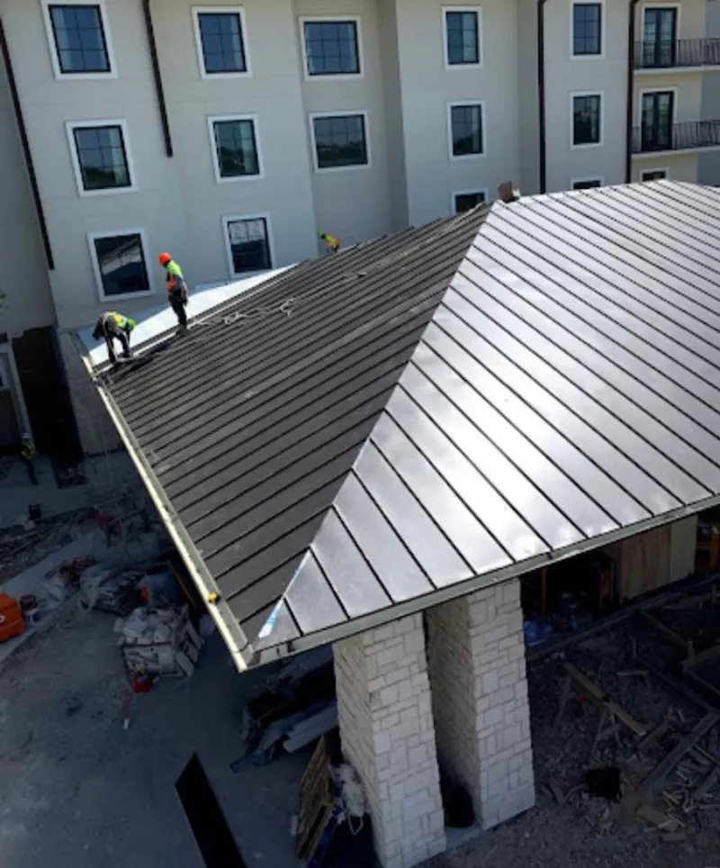 Crew installing standing seam metal roof panels on a commercial project in Newark